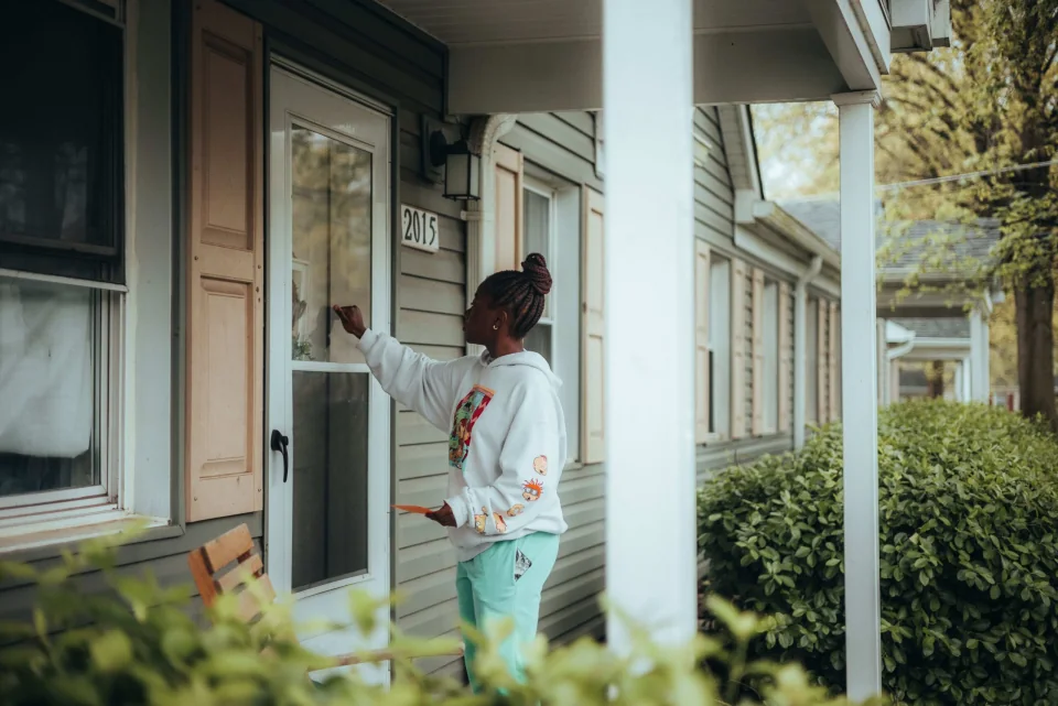 A worker knocking on a residential door during a home visit.