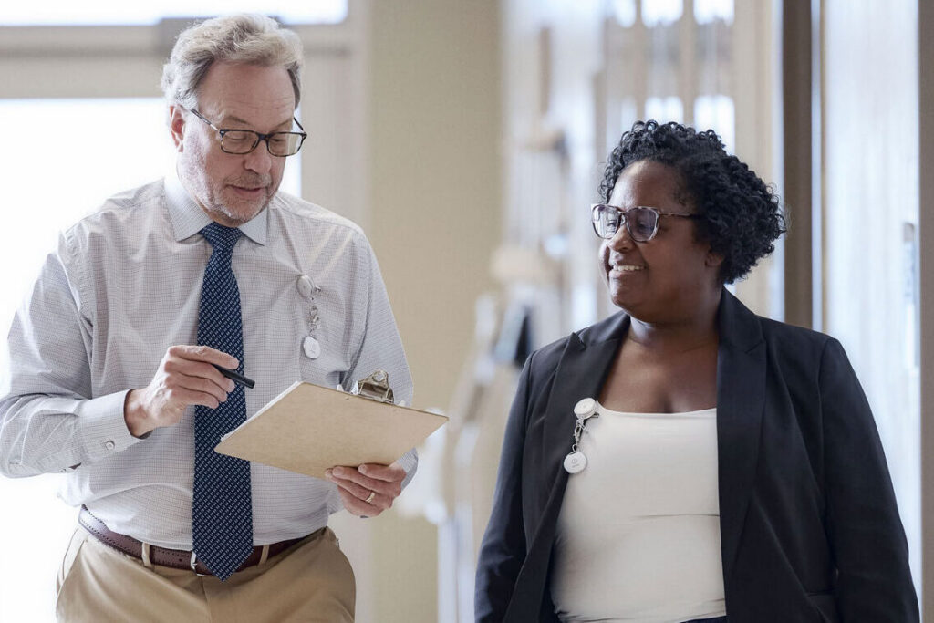 Inspector with a clipboard meeting with a business owner indoors.