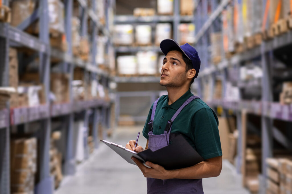 warehouse worker doing inventory control and looking up at shelves with boxes