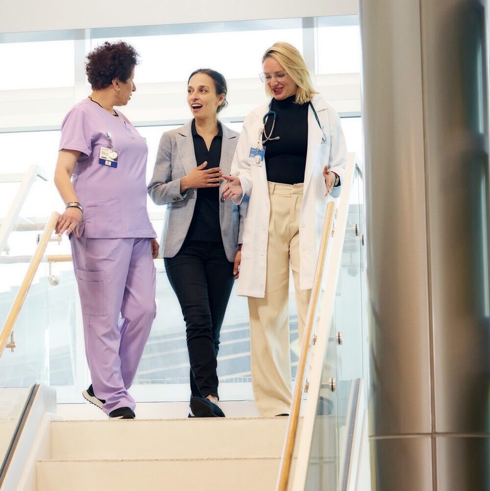 President and Founder Yasmine Mustafa walks down a staircase with a nurse and doctor in a behavioral health center