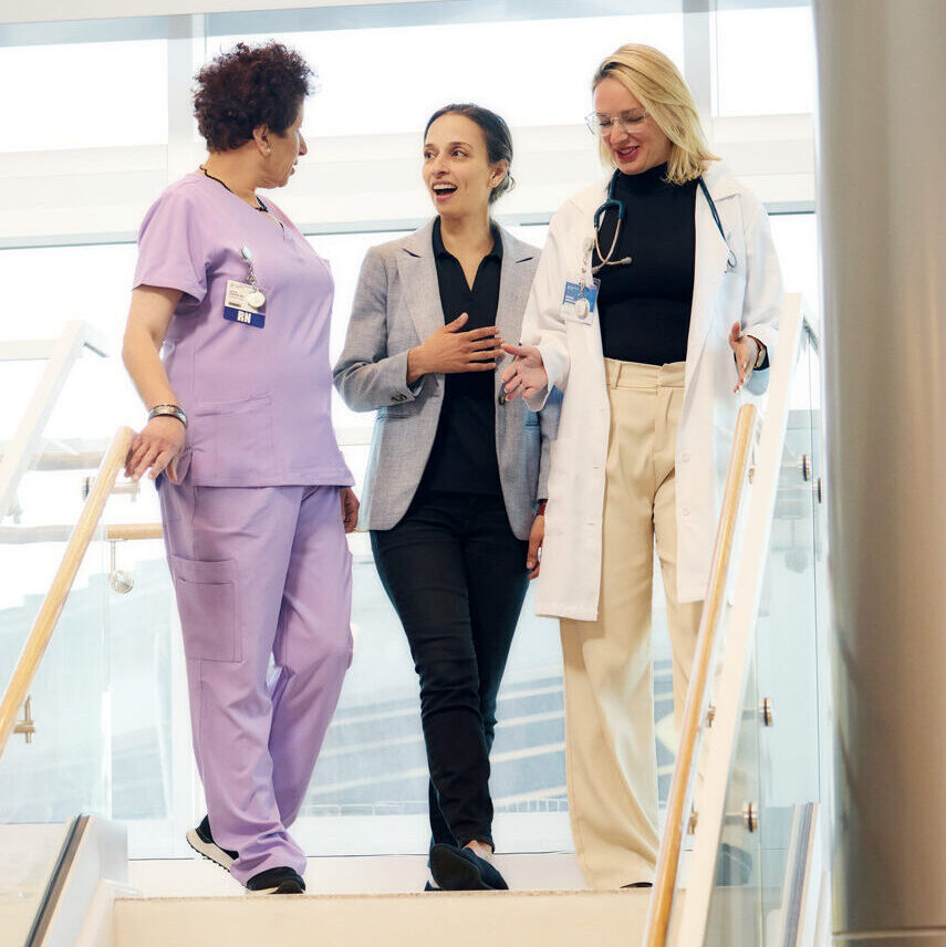 President and Founder Yasmine Mustafa walks down a staircase with a nurse and doctor in a behavioral health center