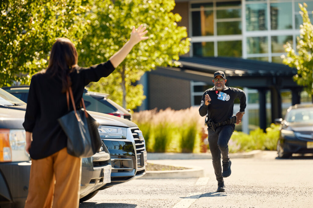 security guard wearing a ROAR Alert Device running toward a woman in a parking lot waving her hand