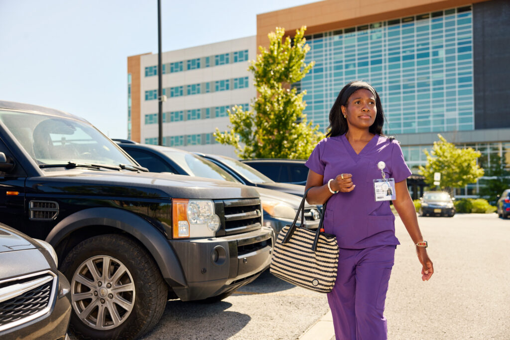 nurse in scrubs walking in a parking lot wearing a ROAR Alert Device on her top
